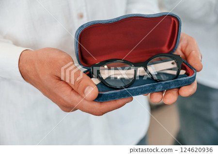 Close up view of man's hands that holding glasses for correcting vision 124620936