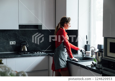 Woman housewife washing dishes in sink in kitchen 124620953