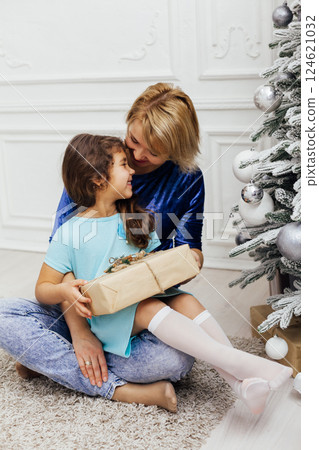 Little Curly girl and Mom at the Christmas Tree with New Year's Gifts 124621032