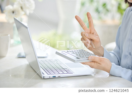 一位中年婦女在客廳一邊使用計算機一邊看著電腦 124621045