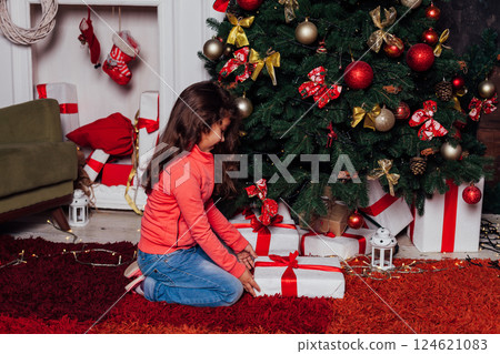 Little Curly Girl at Christmas Tree with New Year Gifts Little Curly Girl at Christmas Tree with New Year Gifts 124621083