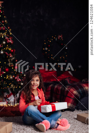 Little Curly Girl at Christmas Tree with New Year Gifts 124621084