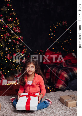 Little Curly Girl at Christmas Tree with New Year Gifts Little Curly Girl at Christmas Tree with New Year Gifts 124621085