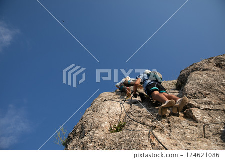 Male and female climbers climbing to the top with belay Male and female climbers climbing to the top with belay 124621086