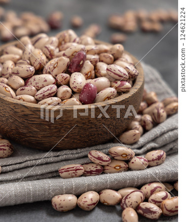 Wooden bowl full of dried pinto beans on napkin on gray closeup. Traditional Latin American legumes Wooden bowl full of dried pinto beans on napkin on gray closeup. Traditional Latin American legumes 124621224