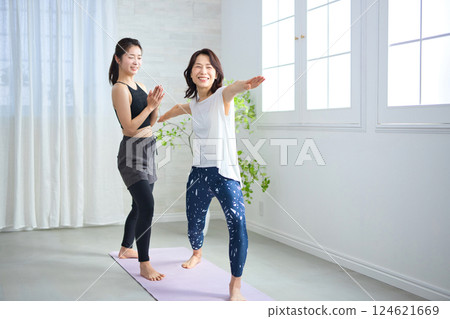 Middle-aged woman receiving lessons from a yoga instructor 124621669