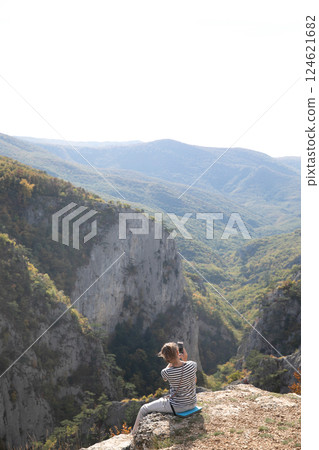 Female tourist taking pictures of forest view from mountain top Female tourist taking pictures of forest view from mountain top 124621682
