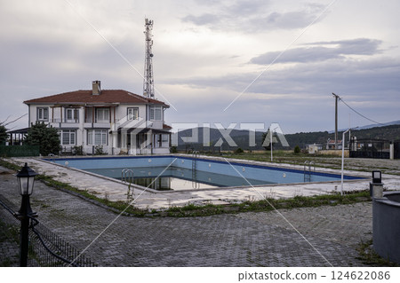 Unkempt and abandoned outside swimming pool near a residential house 124622086