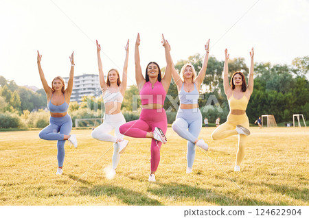 Standing and practicing. Group of women have fitness outdoors on the field together Standing and practicing. Group of women have fitness outdoors on the field together 124622904