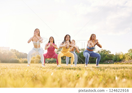 Standing and practicing. Group of women have fitness outdoors on the field together Standing and practicing. Group of women have fitness outdoors on the field together 124622916