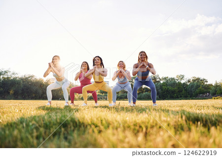 Legs workout. Group of women have fitness outdoors on the field together 124622919