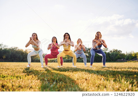 Legs workout. Group of women have fitness outdoors on the field together 124622920