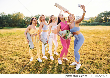 Making selfie by phone. Group of women have fitness outdoors on the field together 124622924