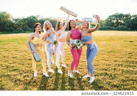 Making selfie by phone. Group of women have fitness outdoors on the field together 124622925