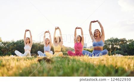 Doing yoga. Group of women have fitness outdoors on the field together Doing yoga. Group of women have fitness outdoors on the field together 124622930