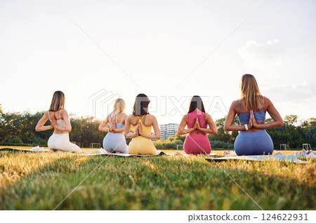 Doing yoga. Group of women have fitness outdoors on the field together Doing yoga. Group of women have fitness outdoors on the field together 124622931