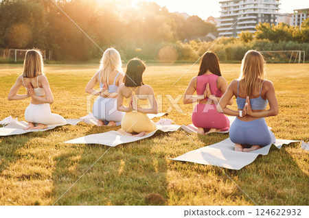 Doing yoga. Group of women have fitness outdoors on the field together 124622932
