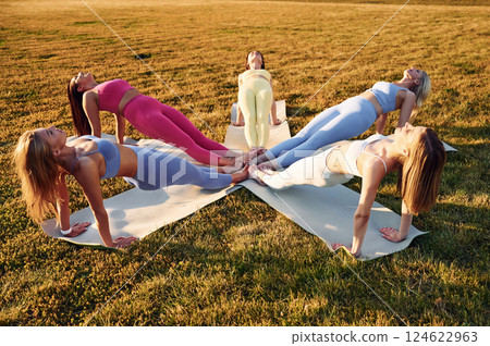 Doing upward plank. Group of women have fitness outdoors on the field together 124622963
