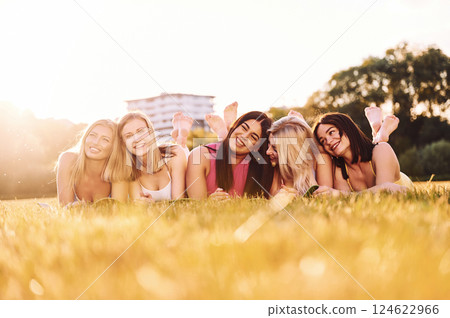 Laying down on the ground and smiling. Group of women have fitness outdoors on the field together Laying down on the ground and smiling. Group of women have fitness outdoors on the field together 124622966