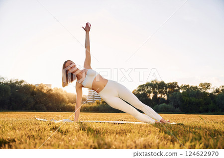 Doing hands practive. Beautiful woman in sportive clothes doing fitness exercises outdoors on the field Doing hands practive. Beautiful woman in sportive clothes doing fitness exercises outdoors on the field 124622970