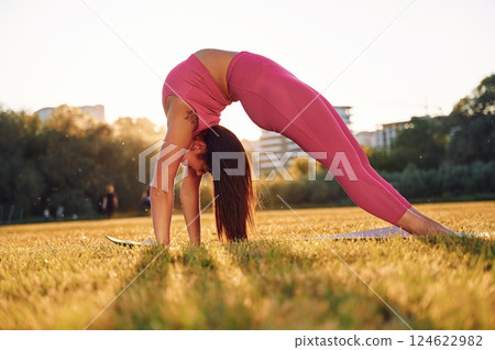 Beautiful woman in sportive clothes doing fitness exercises outdoors on the field 124622982