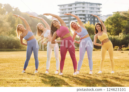 Start of the practice. Does stretch. Group of women have fitness outdoors on the field together 124623101