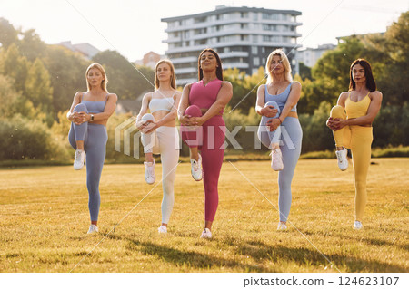 Start of the practice. Does stretch. Group of women have fitness outdoors on the field together 124623107