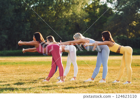 Start of the practice. Does stretch. Group of women have fitness outdoors on the field together Start of the practice. Does stretch. Group of women have fitness outdoors on the field together 124623110