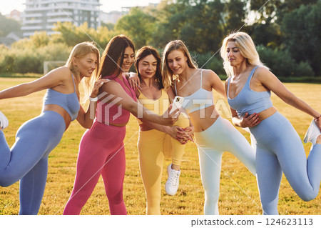 Selfie by a phone. Group of women have fitness outdoors on the field together 124623113