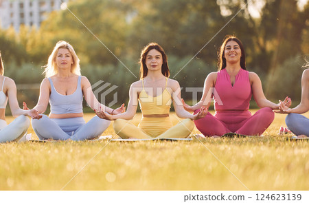 It lotus pose. Group of women have fitness outdoors on the field together 124623139