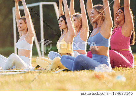 It lotus pose. Group of women have fitness outdoors on the field together 124623140