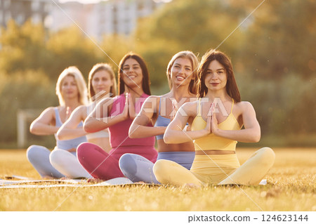 Calm meditation in lotus pose. Group of women have fitness outdoors on the field together 124623144
