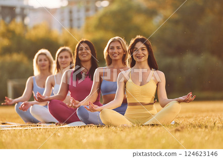 Calm meditation in lotus pose. Group of women have fitness outdoors on the field together 124623146