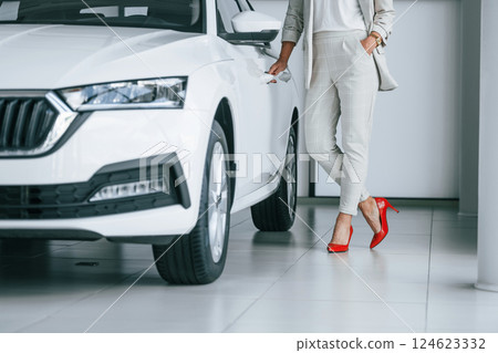 Particle view from below. Woman in white formal clothes is in the car dealership 124623332