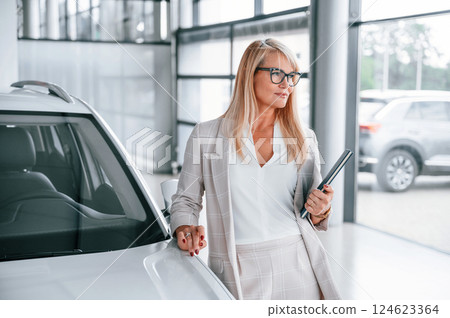 Manager is ready to help. Woman in white formal clothes is in the car dealership 124623364