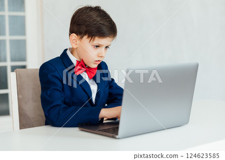 Little boy in business suit sitting at laptop Little boy in business suit sitting at laptop 124623585