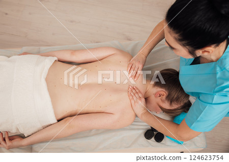 chiropractor giving medical facial massage to woman in spa 124623754