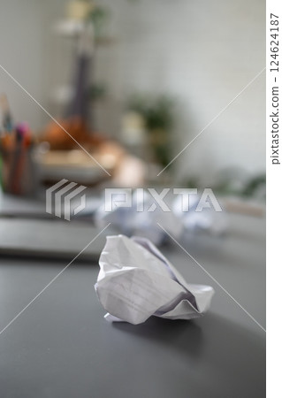 Crumpled paper on messy desk in home interior. Failed ideas, mental clutter, and domestic disorganization in a chaotic living space. 124624187
