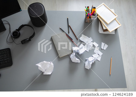 Messy home office desk with scattered paper and supplies. Creative block, frustration and domestic disorder in a modern living space. 124624189