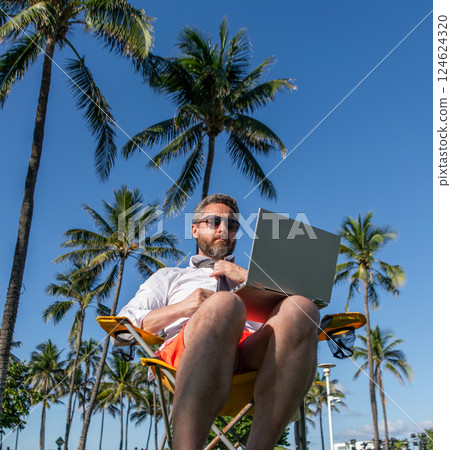 Businessman office worker with laptop. Business man using laptop at palm tree. Business trip. Man freelance worker online at beach. Businessman on summer. Online freelance work Businessman office worker with laptop. Business man using laptop at palm tree. Business trip. Man freelance worker online at beach. Businessman on summer. Online freelance work 124624320