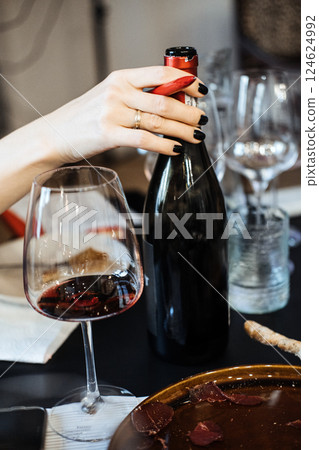 Person opening a wine bottle at a workshop table with red wine and food pairings. Wine workshop, hands-on learning, wine service skills, food and beverage Person opening a wine bottle at a workshop table with red wine and food pairings. Wine workshop, hands-on learning, wine service skills, food and beverage 124624992