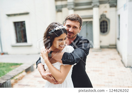 Embracing each other. Beautiful bride with his fiance is celebrating wedding outdoors Embracing each other. Beautiful bride with his fiance is celebrating wedding outdoors 124626202