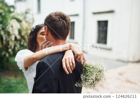 Embracing each other. Beautiful bride with his fiance is celebrating wedding outdoors Embracing each other. Beautiful bride with his fiance is celebrating wedding outdoors 124626211
