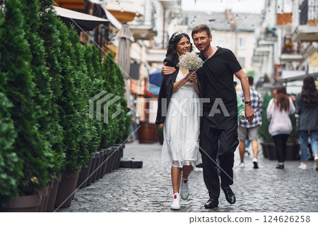 On the street with green plants on the left side. Beautiful bride with his fiance is celebrating wedding outdoors 124626258
