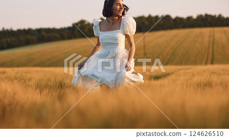 Having a walk. Beautiful young bride in white dress is on the agricultural field at sunny day Having a walk. Beautiful young bride in white dress is on the agricultural field at sunny day 124626510