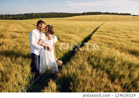 Standing and enjoying the nature. Couple just married. Together on the majestic agricultural field at sunny day 124626524