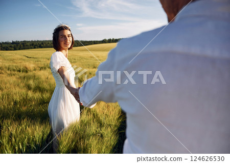 Holding each other by the hands. Couple just married. Together on the majestic agricultural field at sunny day 124626530