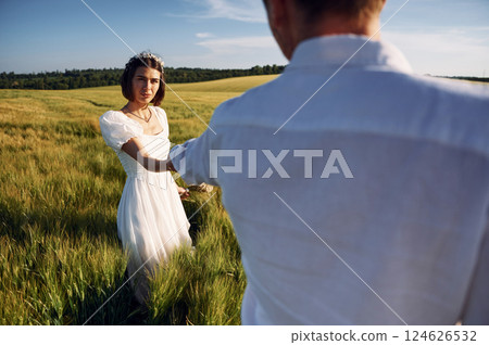 Holding each other by the hands. Couple just married. Together on the majestic agricultural field at sunny day 124626532