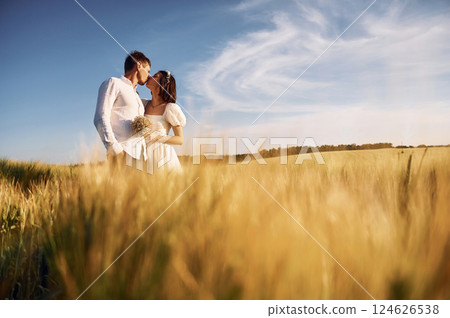 Embracing each other. Couple just married. Together on the majestic agricultural field at sunny day 124626538