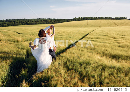 In dress and formal clothes. Couple just married. Together on the majestic agricultural field at sunny day 124626543